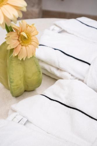 a flower in a vase on a table with white towels at La Mandorla Luxury Trullo in Alberobello