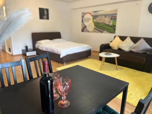 Habitación con mesa, botella de vino y copas en Tranzzit Airport Apartament, en Otopeni