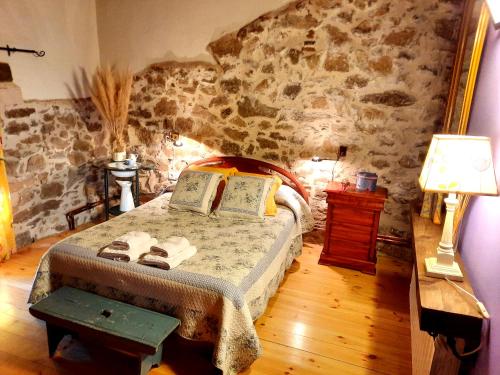 a bedroom with a bed and a stone wall at Casa Rural Alto Santiago in Santiago del Collado