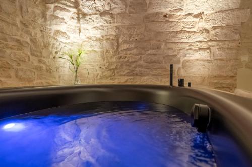 a hot tub in a room with a stone wall at La Mandorla Luxury Trullo in Alberobello