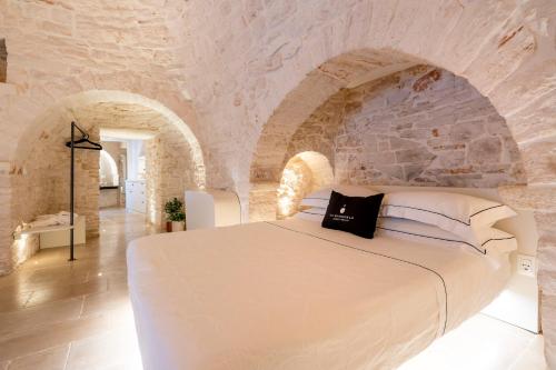 a bedroom with a white bed in a stone wall at La Mandorla Luxury Trullo in Alberobello