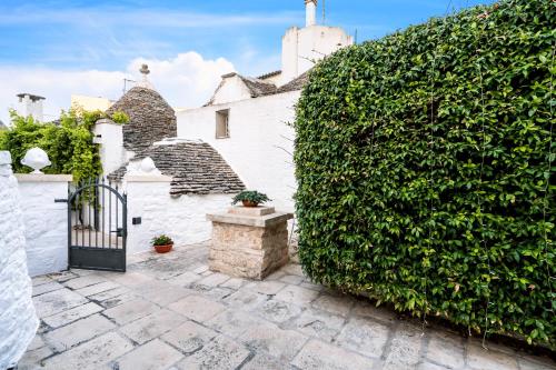 a gate to a white house with a large hedge at La Mandorla Luxury Trullo in Alberobello