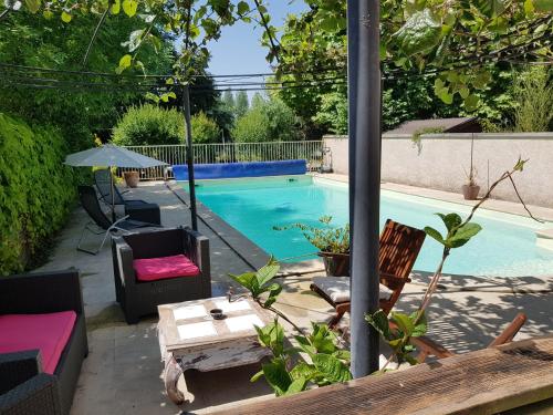 uma piscina com cadeiras e uma mesa em frente em La Villa Bacchus em Groslée