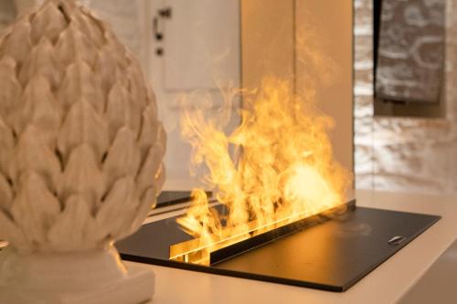 a fire in a fireplace with a statue on a counter at La Mandorla Luxury Trullo in Alberobello