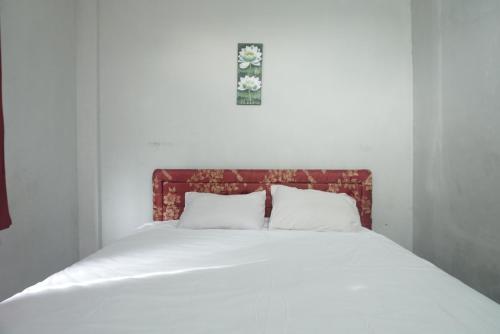 een bed met witte lakens en een kruis erboven bij OYO 93152 Azwa Gh Katingan 