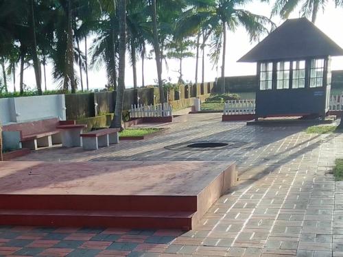 a park with benches and a pavilion with palm trees at Liberty House - SeaView in Kozhikode