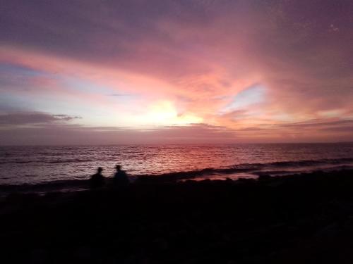 two people sitting on the beach watching the sunset at Liberty House - SeaView in Kozhikode