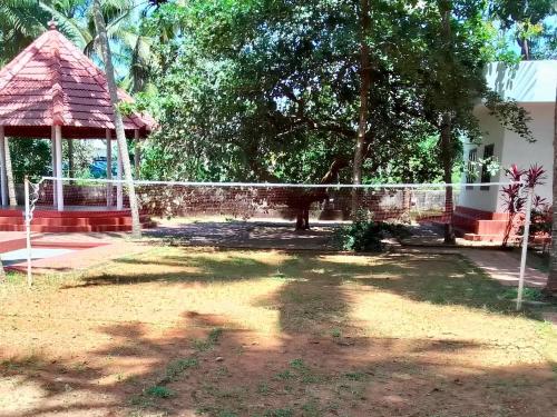 a fence in front of a house with a tree at Liberty House - SeaView in Kozhikode