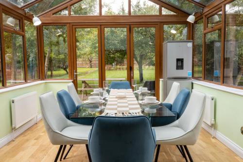 una sala da pranzo con tavolo e sedie in un giardino d'inverno di The Limes a Harston