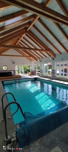 a large swimming pool with a chair in a building at Chambres d’hôtes plateau des mille étangs in Belonchamp