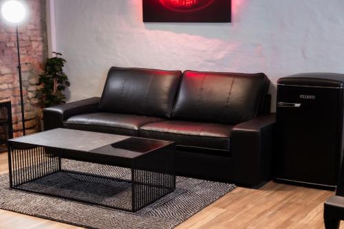 um sofá de couro com uma mesa de centro na sala de estar em BDSM Black Apartments em Vilnius