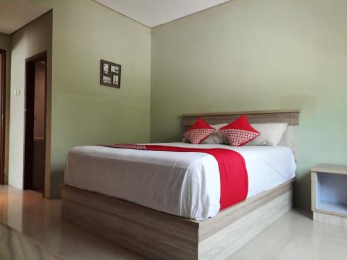 - une chambre avec un grand lit et des oreillers rouges dans l'établissement OYO 93145 Pondok Alam Syariah, à Jakarta