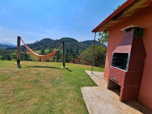 a house with a hammock on the side of it at Pousada Vale das Araucárias in Santo Antônio do Pinhal