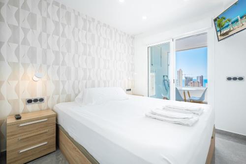 a white bedroom with a large bed and a window at Gemelos 22-3-21D Apartment Deluxe Levante Beach in Benidorm