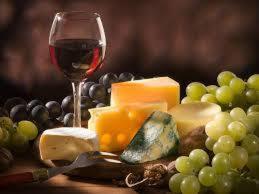 a glass of wine and a bunch of cheese and grapes at Logis Hôtels Troglododo in Azay-le-Rideau