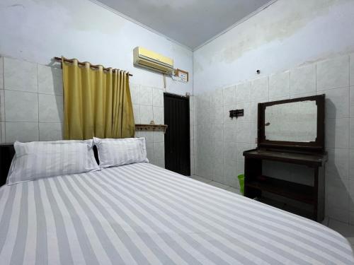 - une chambre avec un lit, une commode et un miroir dans l'établissement OYO 93137 Kost Maharaja, à Makassar