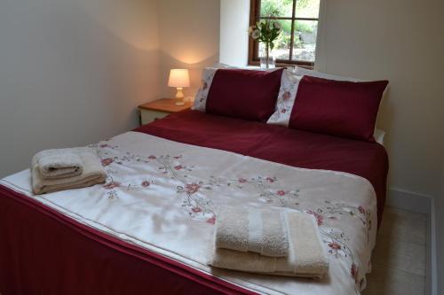 a bed with red and white sheets and towels on it at Ashes Farm - Ingleborough View cottage in Settle