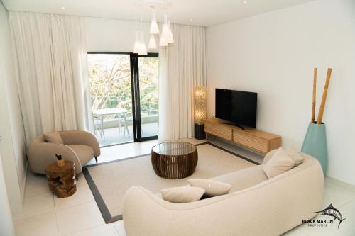 ein Wohnzimmer mit einem Sofa und einem TV in der Unterkunft Black Marlin Apartments in Pereybere