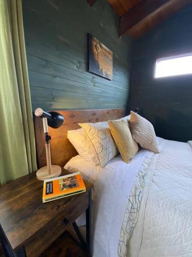 a bedroom with a bed and a table with a book at Espíritus del Cañi. Tiny home y destilería in Pucón