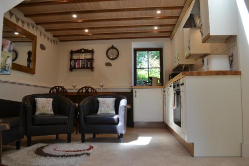 a living room with two chairs and a kitchen at Ashes Farm - Ingleborough Barn Cottage, with 3 peaks views, near Settle in Settle