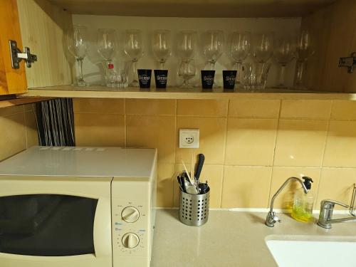 a kitchen with glasses on a shelf above a microwave at Apartment 4 Rooms נוה שאנן in Haifa