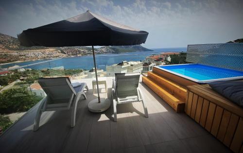 two chairs and an umbrella on a deck with a swimming pool at Rhapsody Hotel & Spa Kalkan in Kalkan