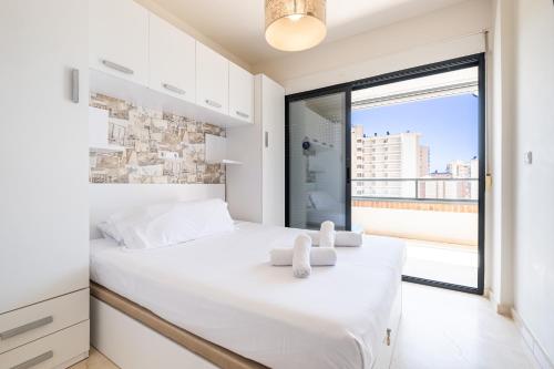 - une chambre avec un lit blanc et une grande fenêtre dans l'établissement Gemelos 23 - 10B Apartment Levante Beach, à Benidorm