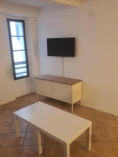 une pièce avec une table et une télévision sur un mur dans l'établissement Budgetbnb 181, à Toulon