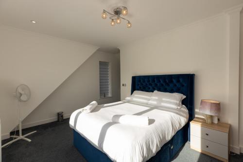a bedroom with a large bed with a blue headboard at The Mayfair in Six Mile Bottom