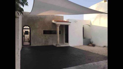 a white house with a gate and a building at La casa de Leslie - Apartment 2 in Mérida