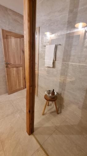 a bathroom with a shower with a table and a door at Guest Accommodation Butina in Kuterevo