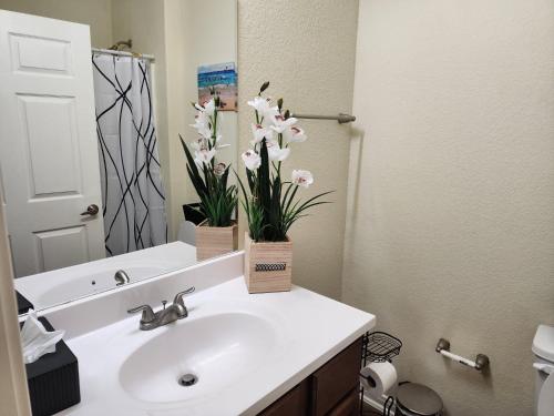 a bathroom with a sink with flowers in a mirror at Spacious and comfortable Villa 4BD/2BA (10 sleeps) in Galveston