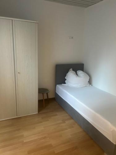 um quarto com uma cama com lençóis brancos e almofadas em Ferienwohnung Siegen Eiserfeld 5 em Siegen