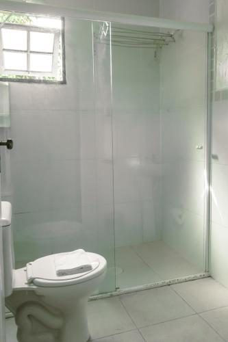 a bathroom with a toilet and a glass shower at Vila dos Tupinambás in Boicucanga