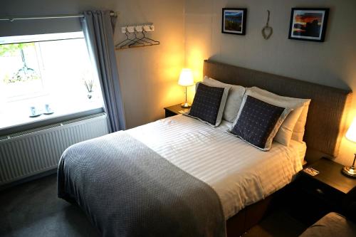 a bedroom with a bed with two pillows and a window at Lundie View B & B in Invergarry