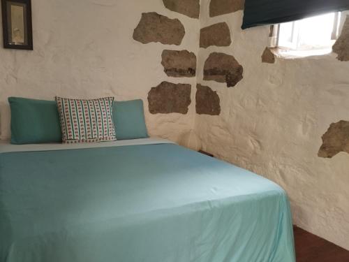 een bed in een kamer met een stenen muur bij Holy House in Santa Brígida