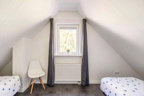 - une chambre mansardée avec 2 lits et une fenêtre dans l'établissement Modern Luxury villa, à Zeewolde