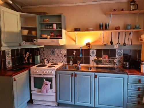 eine Küche mit blauen Schränken, einer Spüle und einem Herd in der Unterkunft Arctic Circle Cabin in Överkalix