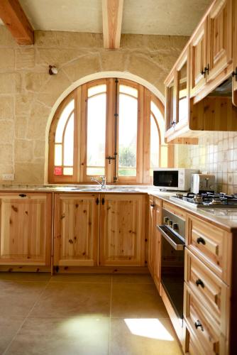 a kitchen with wooden cabinets and a large window at Mill House in Għarb
