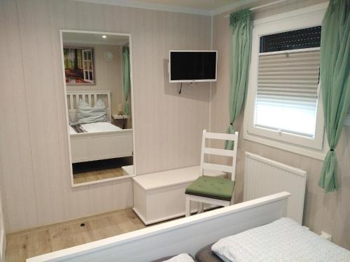 um quarto com um espelho, uma cama e uma cadeira em Tiny Bungalow Visselhövede em Visselhövede