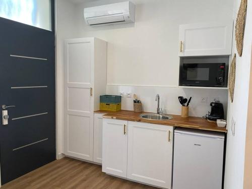 een kleine keuken met witte kasten en een wastafel bij Narbonne : Logement idéalement situé in Narbonne