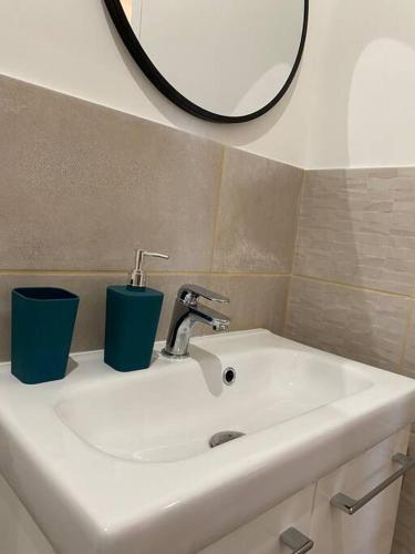 een wastafel in de badkamer met 2 kopjes en een spiegel bij Narbonne : Logement idéalement situé in Narbonne