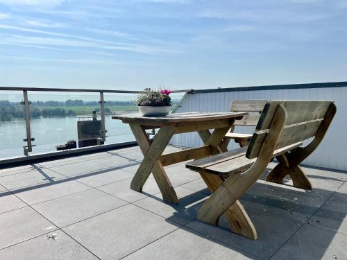 a wooden picnic table and bench on a deck overlooking the water at PANORAMA - Exklusives Apartment an der Promenade mit Dachterrasse & Rheinblick in Emmerich