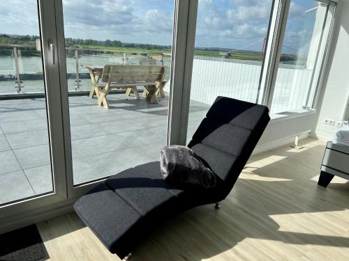 une chaise dans une chambre avec vue sur l'eau dans l'établissement PANORAMA - Exklusives Apartment an der Promenade mit Dachterrasse & Rheinblick, à Emmerich