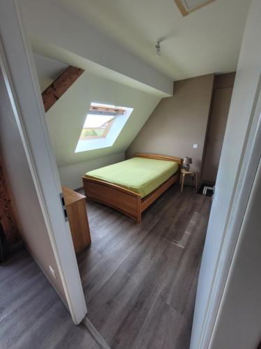 Cette chambre mansardée comprend un lit et une lucarne. dans l'établissement Gîte Au Calme, à Eglingen