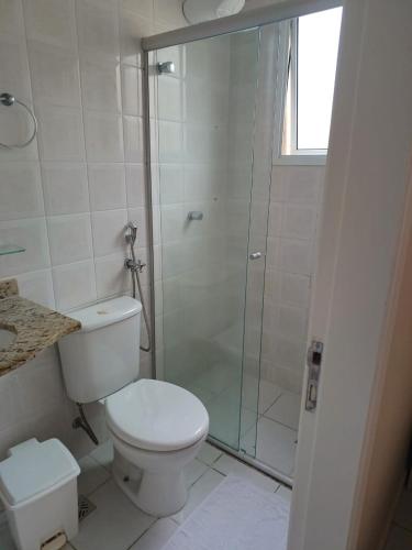 a bathroom with a toilet and a glass shower at Apartamento da Martha in Ubatuba