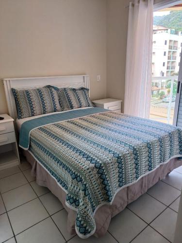 a bedroom with a large bed with a window at Apartamento da Martha in Ubatuba