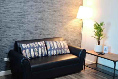 a black leather couch in a room with a table and a lamp at 7min BKK airport - free pick up - malls nearby in Bangkok
