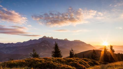 a sunset over a mountain range with the sun setting at Das Gertraud in Filzmoos