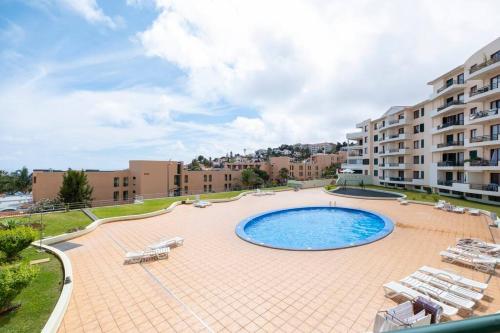 a large swimming pool with lounge chairs and a building at Sarah's Apartment by GALMI in Caniço